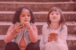Two children sitting on steps eating biscuits