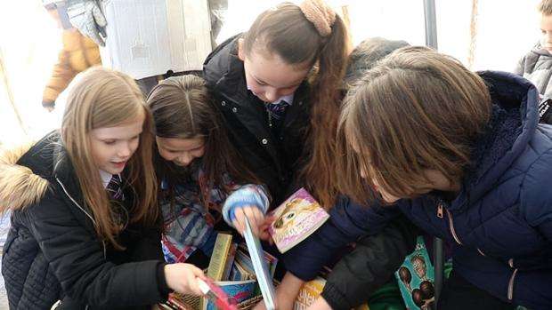 Four pupils looking through a pile of books