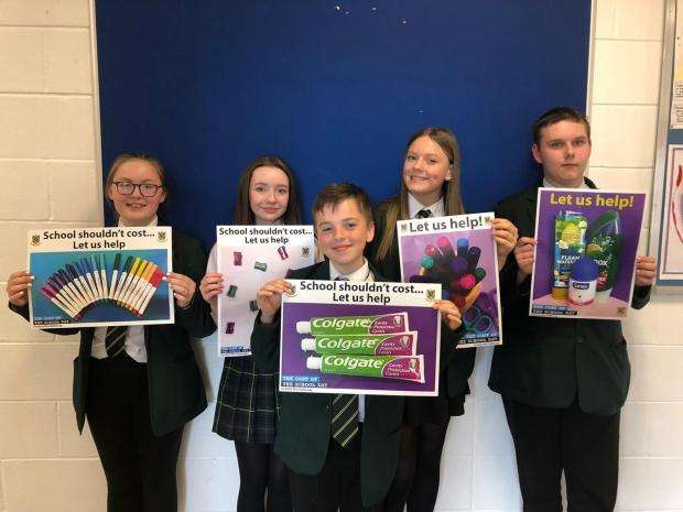 Secondary school aged students holding up posters to tackle poverty