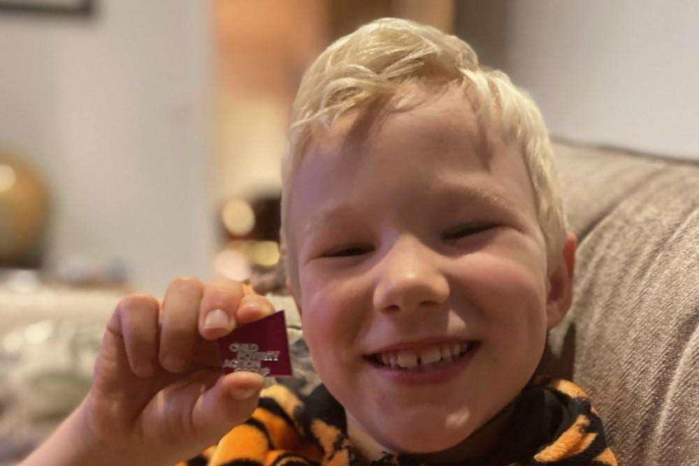 Boy smiling to camera holding Child Poverty Action Group badge
