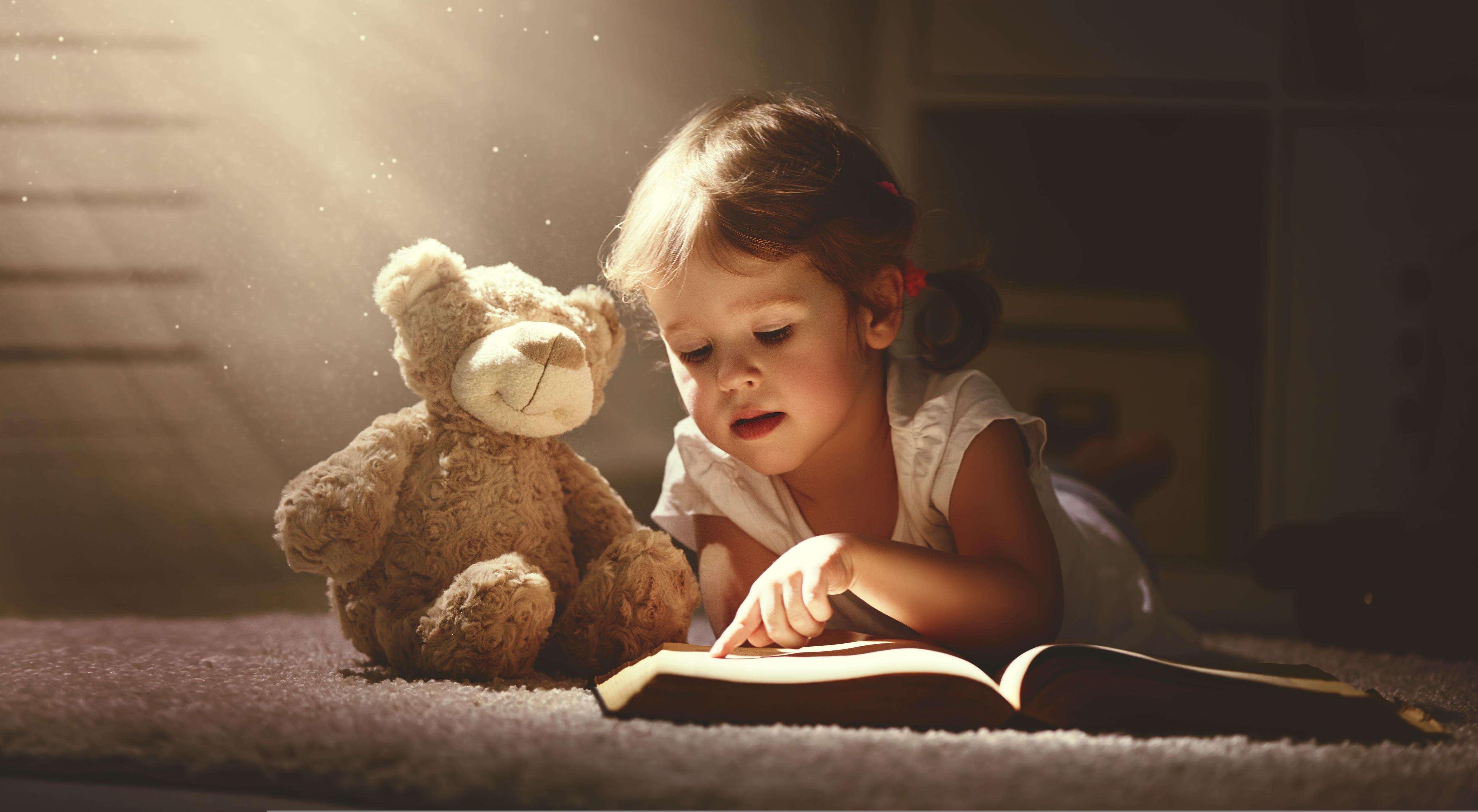 Young girl reading to her teddy