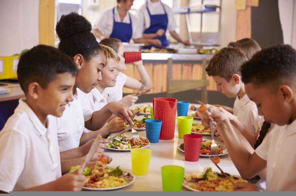 group of school pupils eating lunch around a table