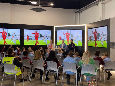 A group of children in front of a panel of speakers