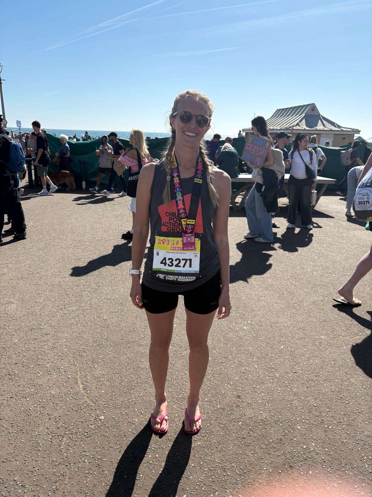 Female marathon runner wearing sunglasses smiling for a photo.