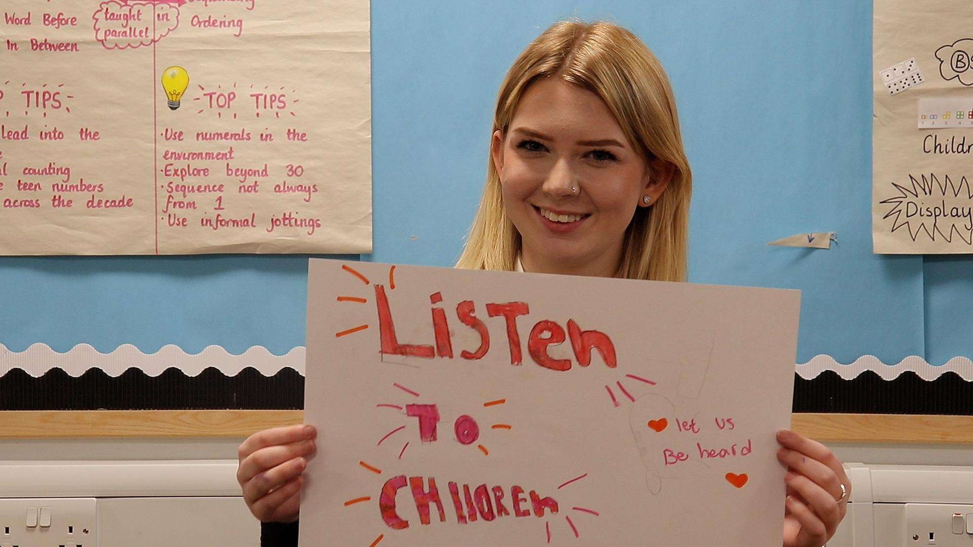 Young person holding up a sign reading listen to children