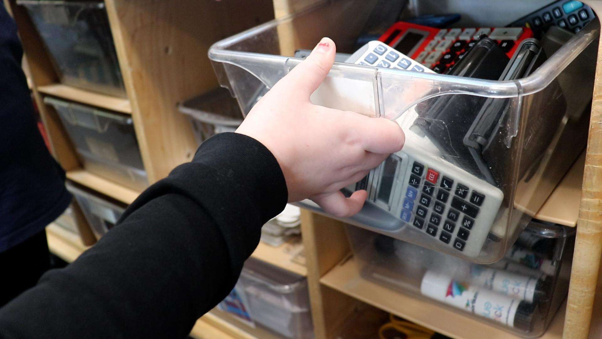 Picture of hand reaching out to open a drawer of calculators
